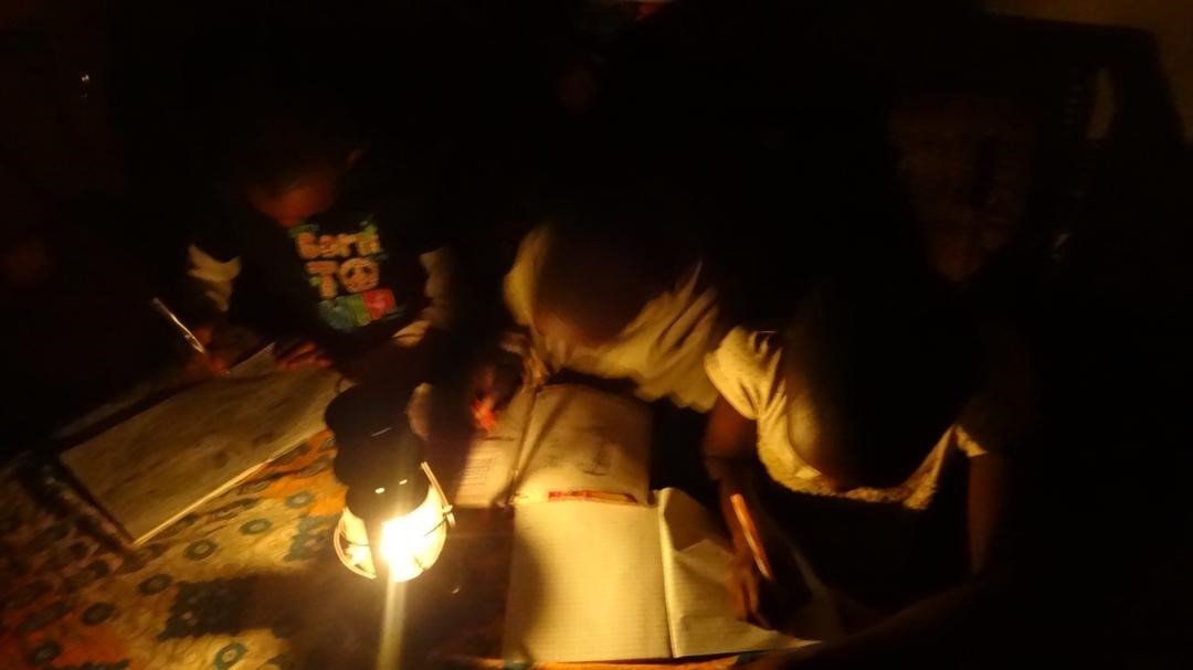 Children studying with kerosene lamp